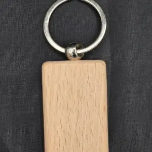 A rectangular wooden keychain with a metal ring on a black background.
