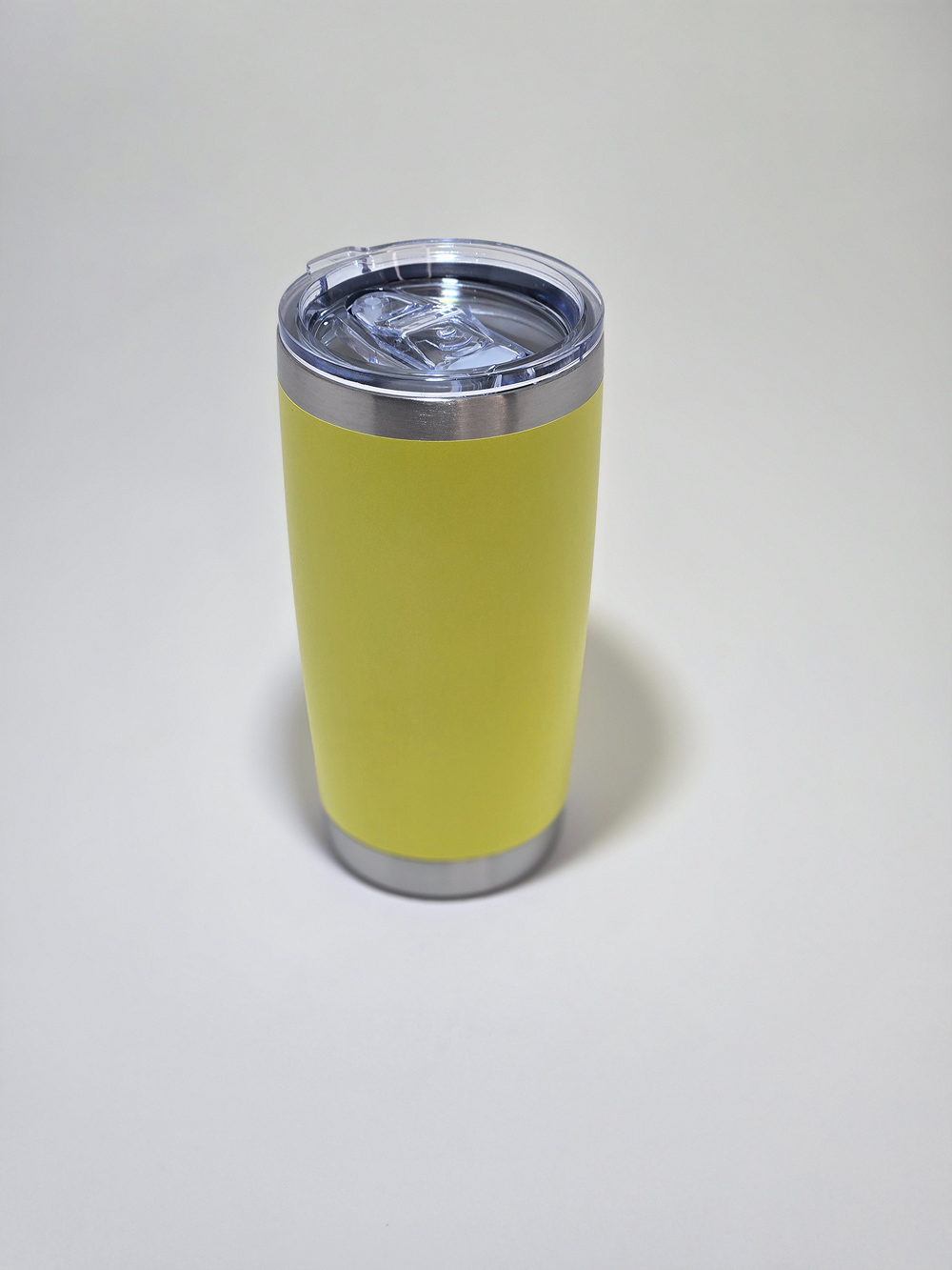 Yellow insulated tumbler with a clear lid on a white surface.