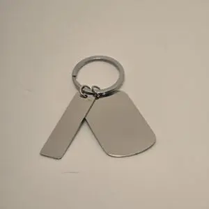 A silver keychain with two blank metal tags on a plain background.