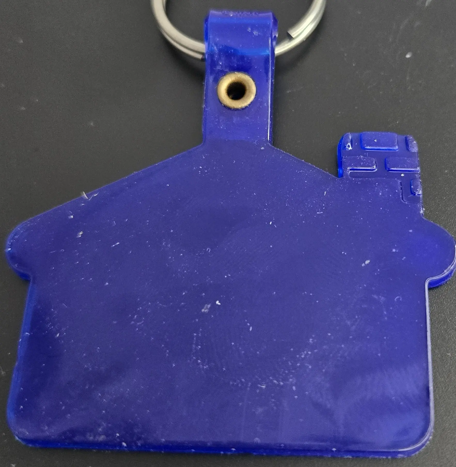 Blue house-shaped keychain on a black surface.