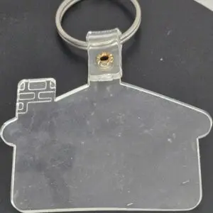 Clear house-shaped keychain on a dark surface.