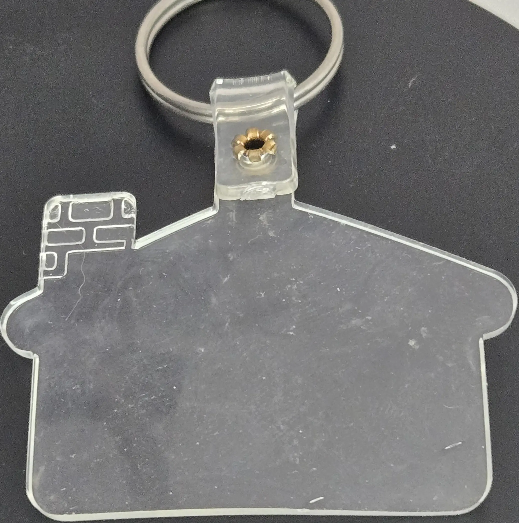 Clear house-shaped keychain on a dark surface.