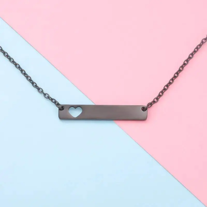 Minimalist silver necklace with a heart cutout pendant on a two-tone background.