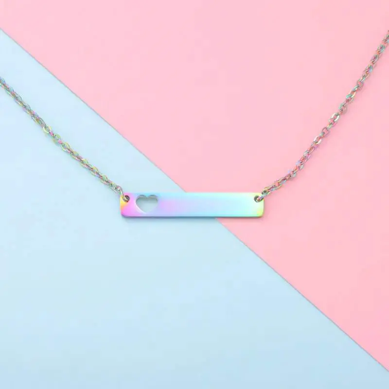 Minimalist rectangular pendant necklace with a small red heart on a pastel pink and blue background.