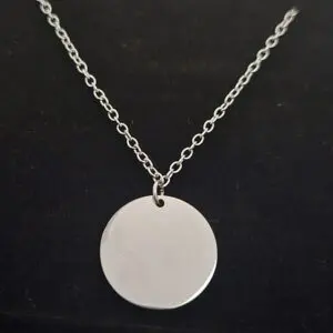 Silver necklace with a round blank pendant on a black background.