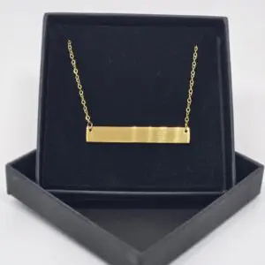 Gold bar necklace displayed in a black box.