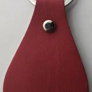 Close-up of a red leather keychain with a silver rivet.
