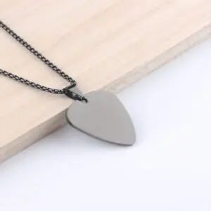 Guitar pick necklace on wooden surface.