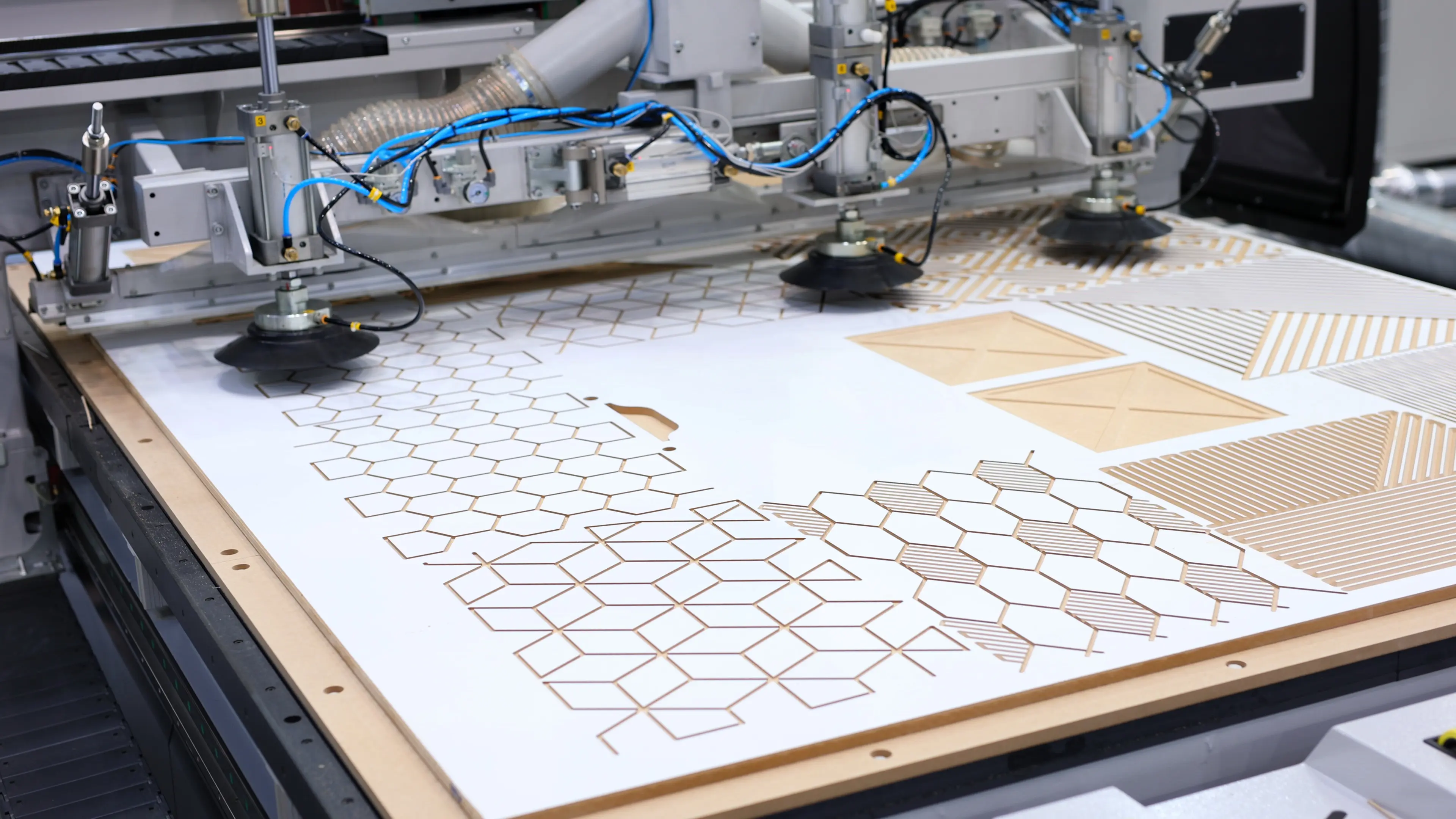 Automated machine cutting intricate hexagonal patterns on material.