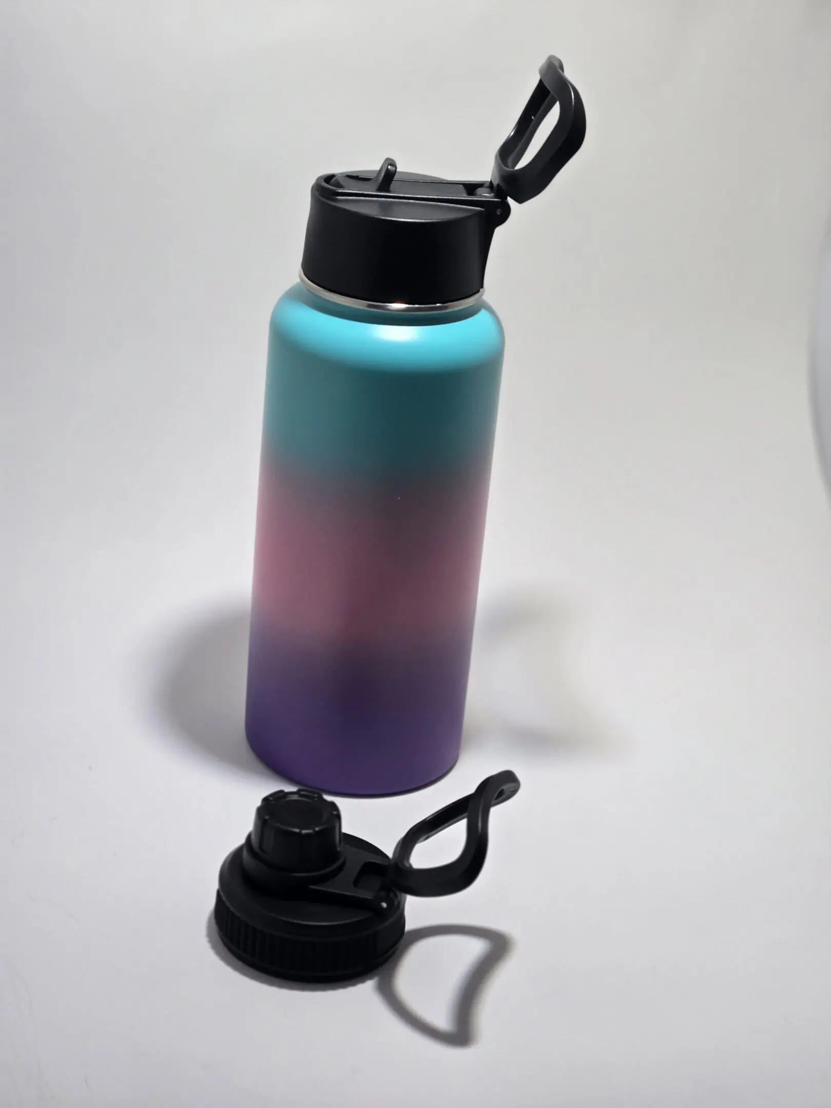 Color-gradient water bottle with black lid and handle.