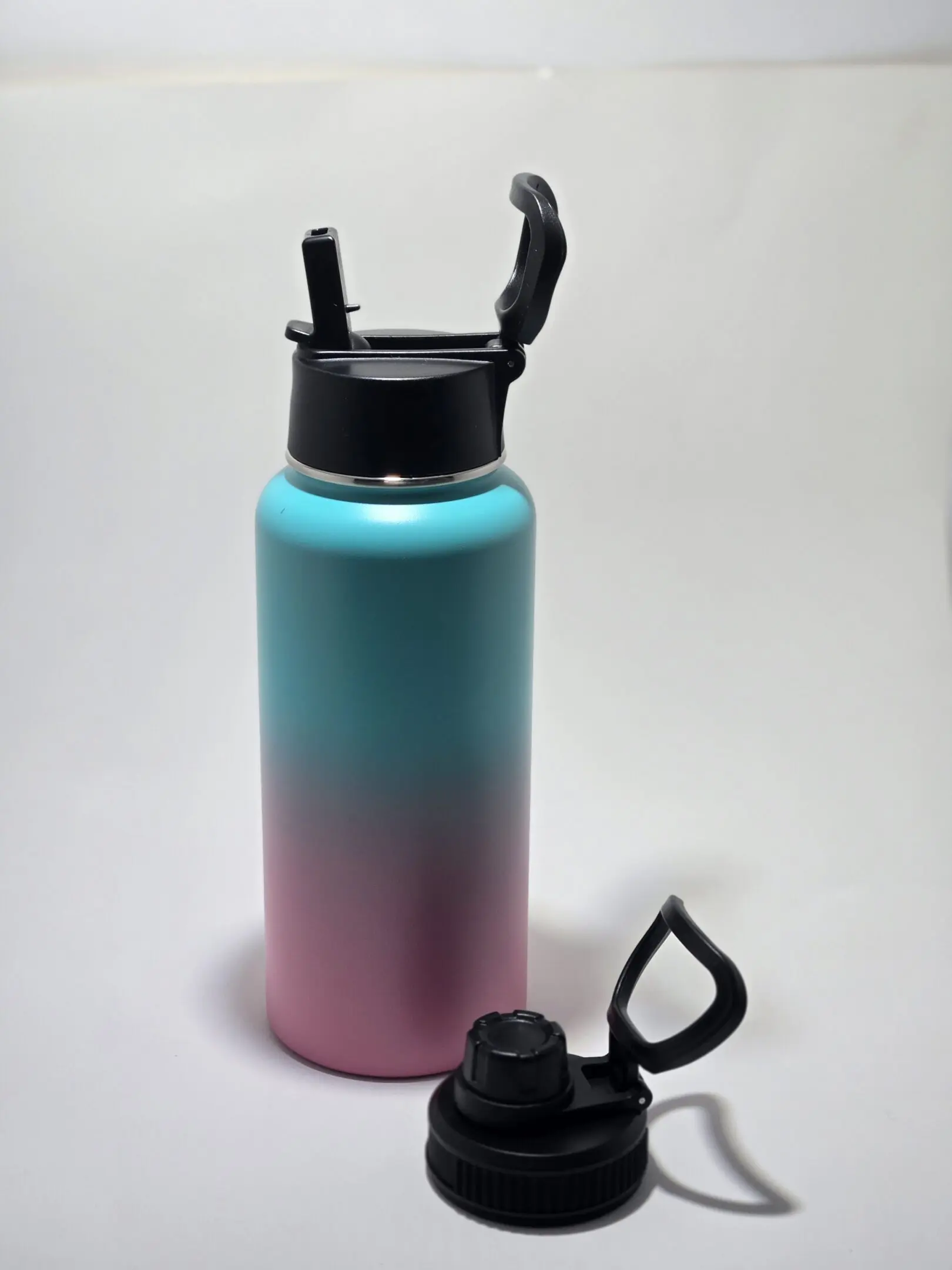 Gradient blue to pink water bottle with black lid and flip cap.