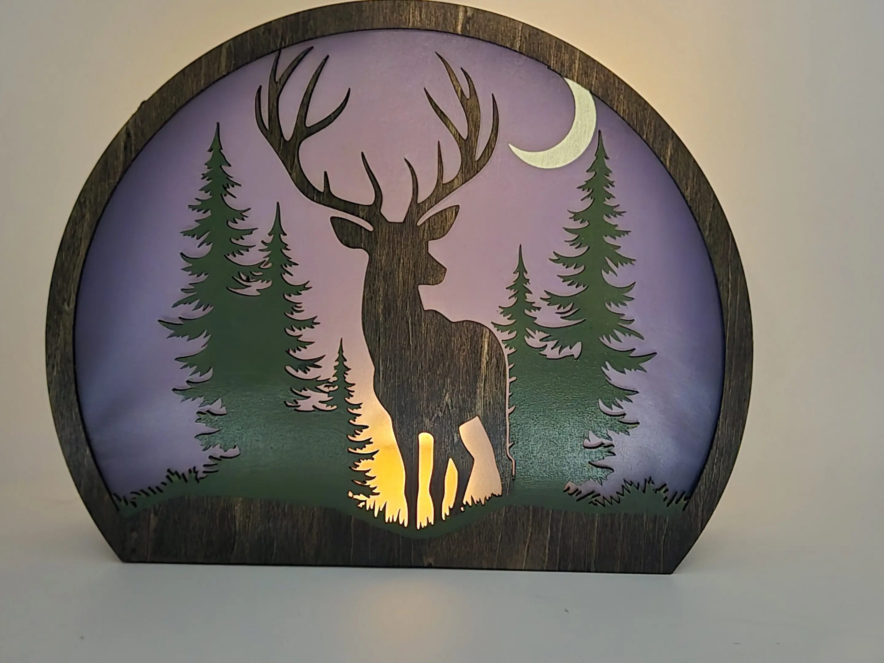 Backlit wooden deer silhouette with crescent moon