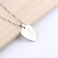 Silver shield-shaped pendant necklace on a wooden surface.