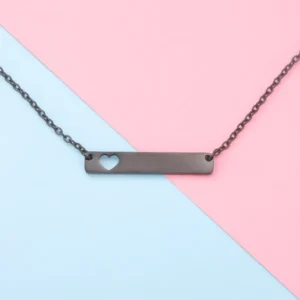 Minimalist bar necklace with a small heart cutout on a pastel pink and blue background.