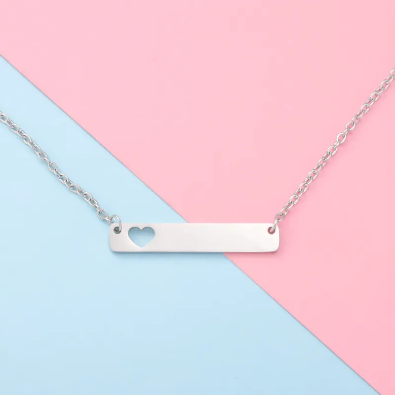 Elegant silver bar necklace with a small heart detail on a pastel pink and blue background.