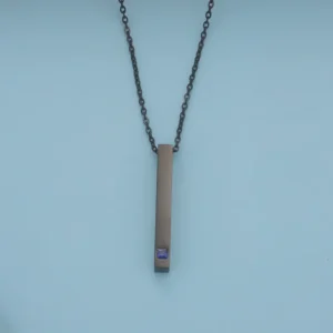 Minimalist necklace with a pendant and small purple accent.