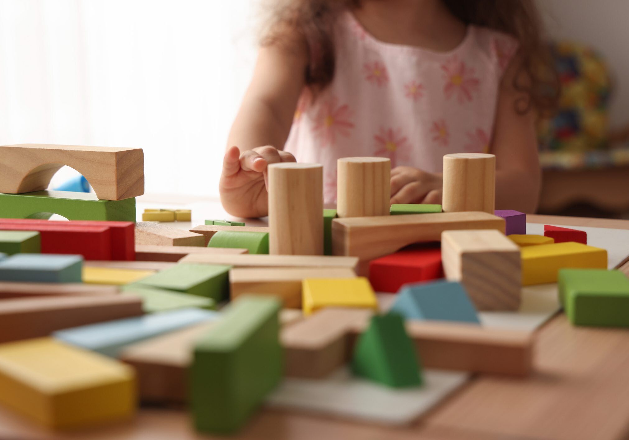 Child playing with colorful wooden building blocks on a table.